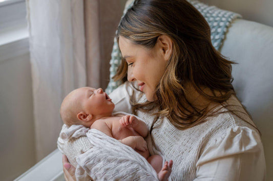 Mother gently holding her newborn wrapped in a soft towel after the first bath.