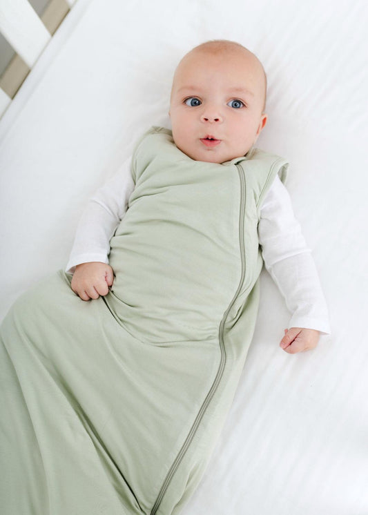 Baby sleeping peacefully in an organic cotton sleeping bag in a neutral nursery