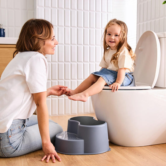 Mother encouraging her toddler during potty training in a bright modern bathroom.